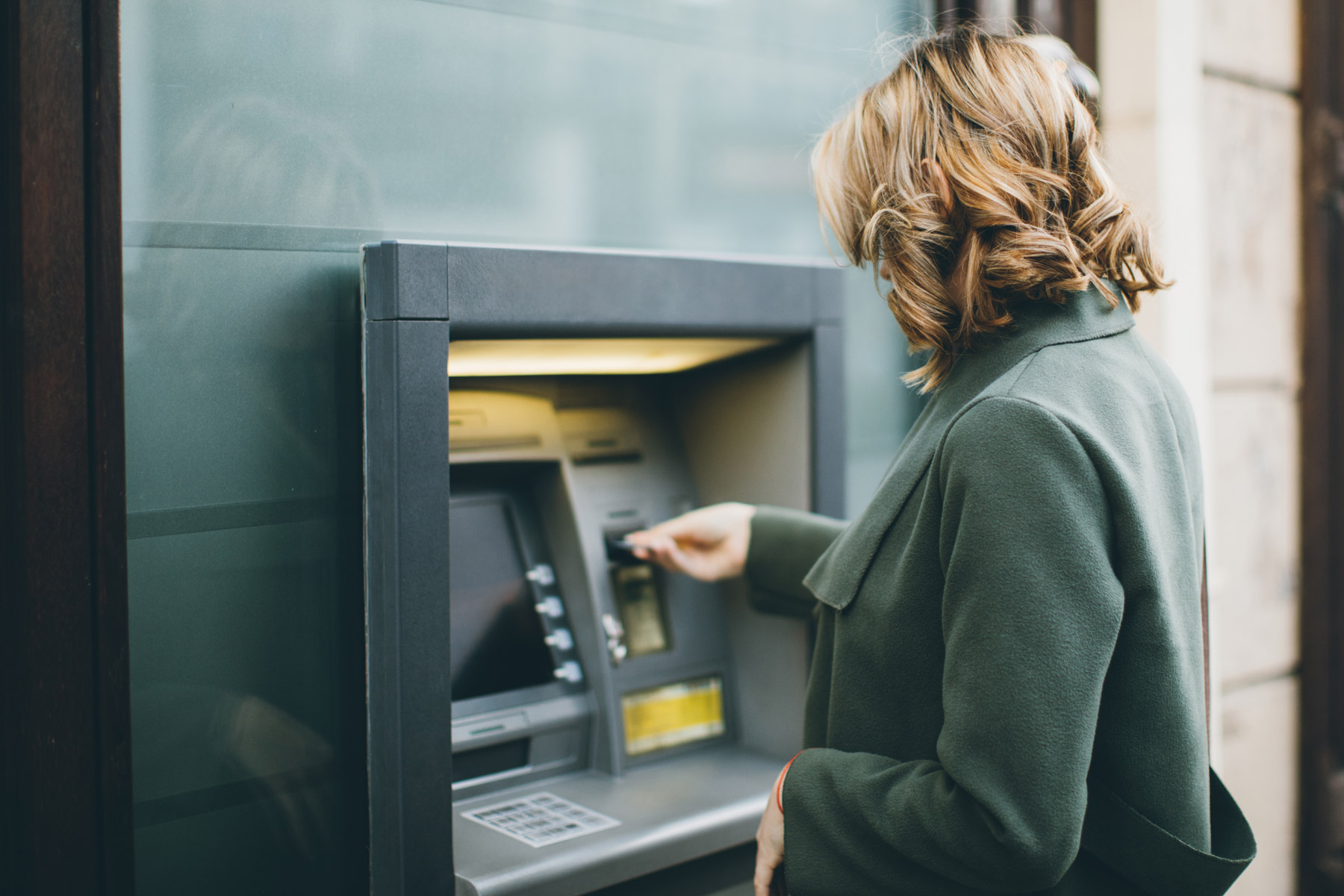 Frau hebt Geld ab an Postomat