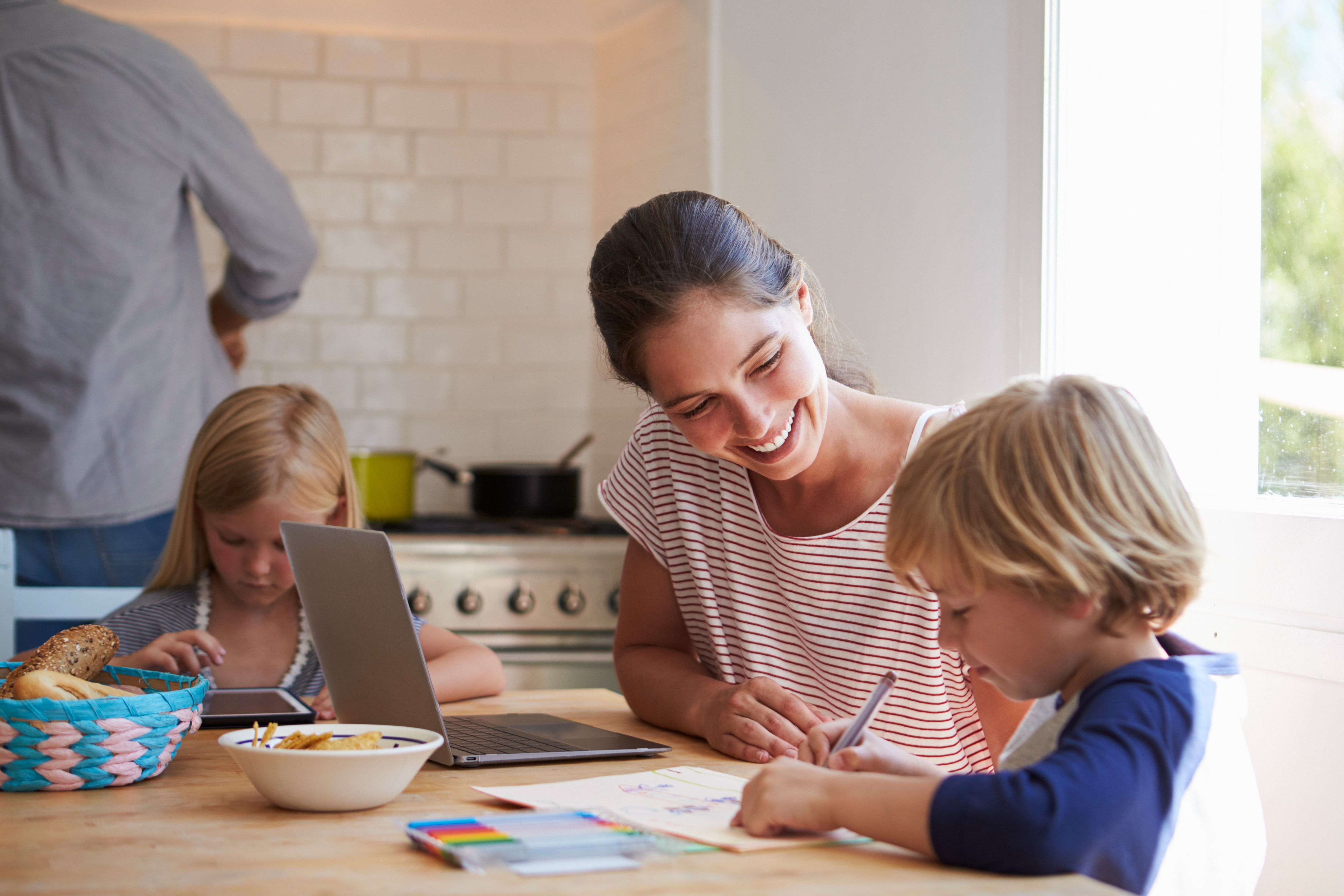 Kids doing homework at kitchen table with mum, close up